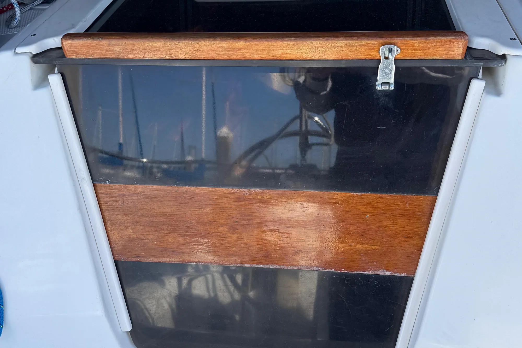 Wooden hatch door on a 1994 Hunter 29.5 sailboat, with marina reflections.