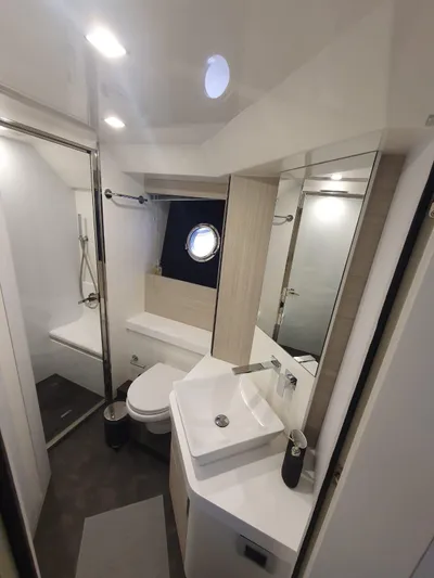  Yacht Photos Pics Modern bathroom in 2023 Cranchi E52F yacht with sleek fixtures and porthole window.