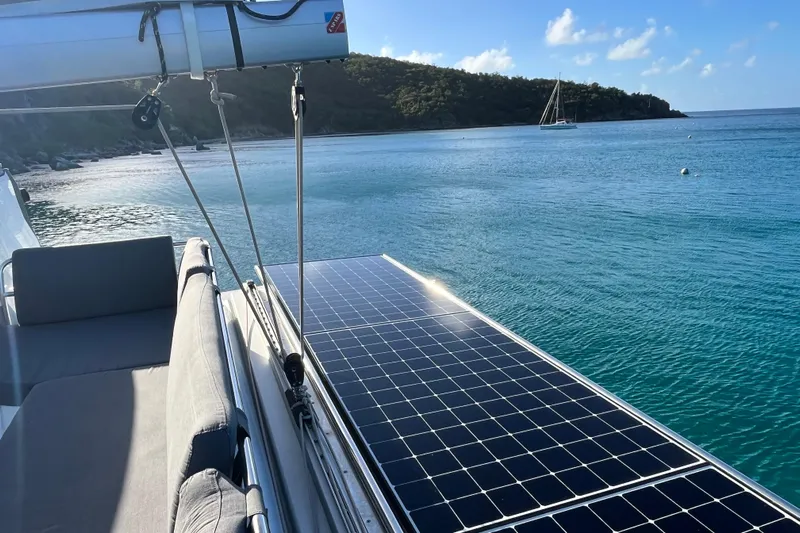 Family Therapy Yacht Photos Pics 2023 Fountaine Pajot Elba 45 Catamaran with solar panels, anchored in serene coastal waters.