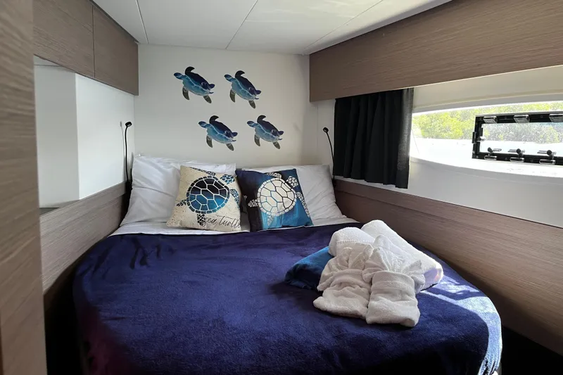 Family Therapy Yacht Photos Pics 2023 Fountaine Pajot Elba 45 Catamaran cabin with cozy bed and sea turtle decor.
