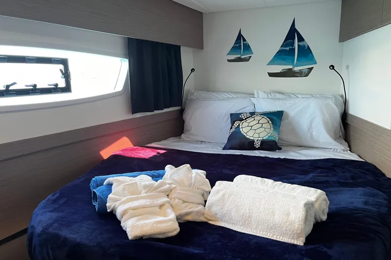 Family Therapy Yacht Photos Pics Luxurious bedroom in 2023 Fountaine Pajot Elba 45 Catamaran with nautical decor and plush bedding.