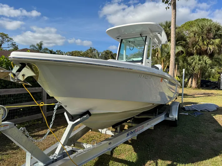  Yacht Photos Pics 2024 Everglades 253 Center Console boat on trailer, surrounded by palm trees.