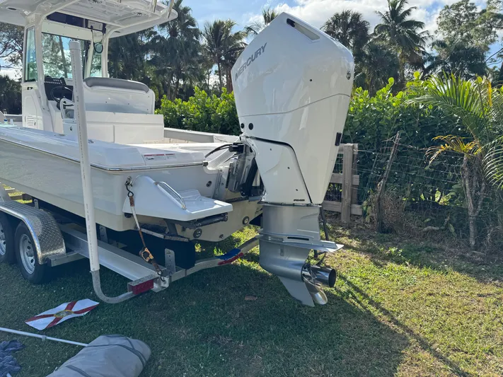  Yacht Photos Pics 2024 Everglades 253 Center Console boat on trailer, surrounded by lush greenery.