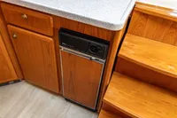 Wooden interior of 2005 Vripack Spiegelkotter 14.50 yacht with compact fridge and stairs.