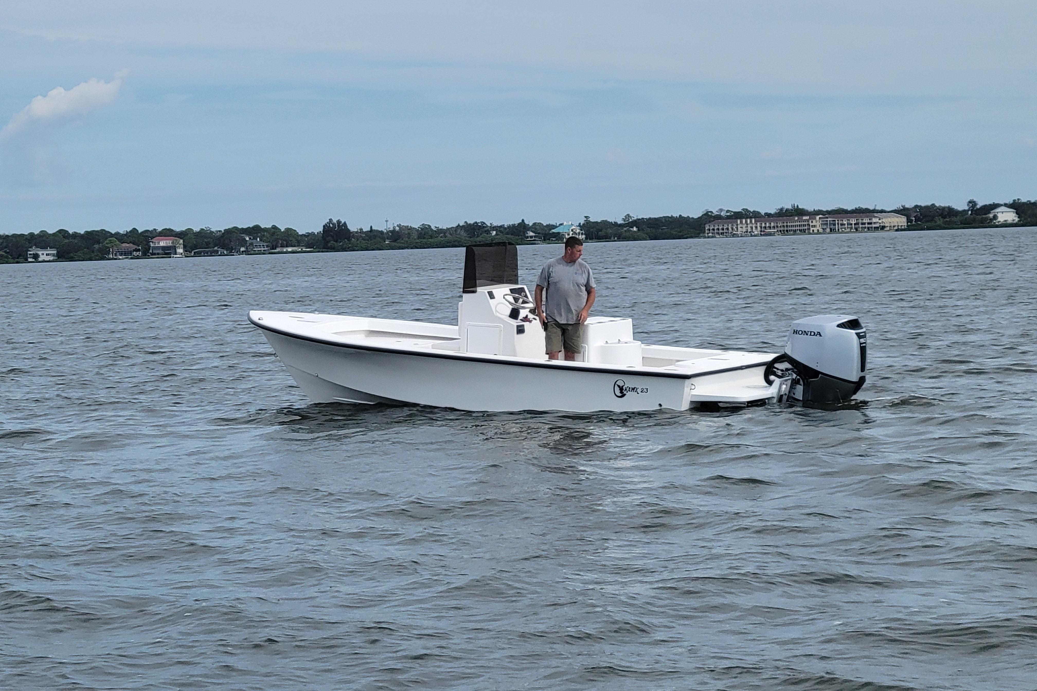 2025 C-Hawk 23CC boat on water with person standing, Honda outboard motor.