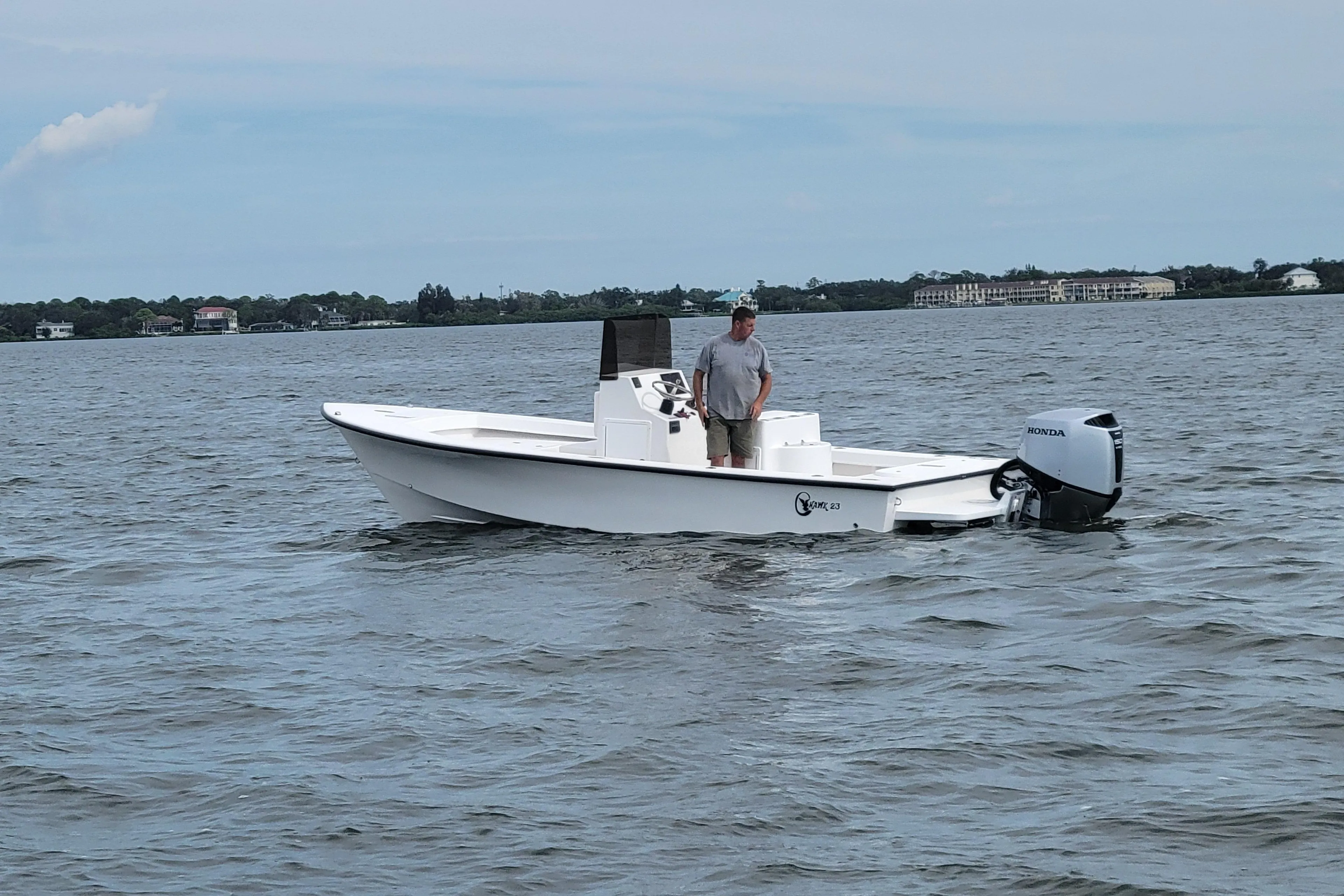 2025 C-Hawk 23CC boat on water with person standing, Honda outboard motor.
