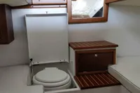 2023 Gozzo Positano 27 Open boat interior with compact marine toilet and wooden cabinetry.