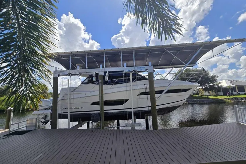  Yacht Photos Pics 2020 Regal 38 XO yacht on lift, dockside, under blue sky and palm trees.