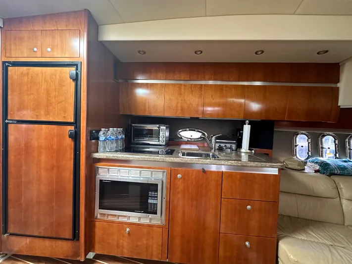 No Dploma Yacht Photos Pics 2009 Cruisers Yachts 420 Express kitchen with wood cabinets, microwave, and refrigerator.