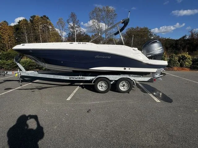2023 Hurricane SunDeck Sport 205 OB boat on trailer in parking lot, clear sky background.