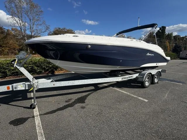 2023 Hurricane SunDeck Sport 205 OB boat on trailer in parking lot.