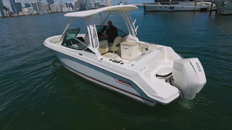  Yacht Photos Pics 2023 Boston Whaler 240 Vantage boat cruising on water near city skyline.