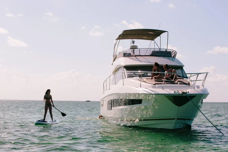  Yacht Photos Pics Prestige 460 yacht with people relaxing, paddleboarder nearby, sunny day on the ocean.