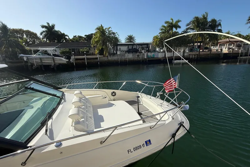  Yacht Photos Pics 2022 Sea Ray Sundancer 320 Outboard docked by waterfront homes, featuring American flag.