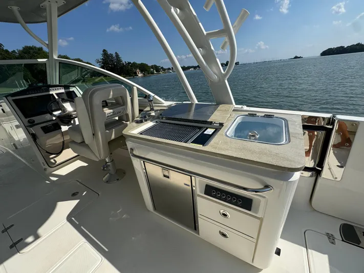  Yacht Photos Pics 2023 Boston Whaler 320 Vantage boat interior with helm, grill, and sink by the water.