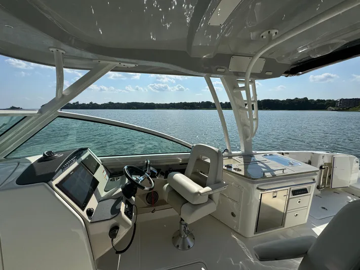  Yacht Photos Pics 2023 Boston Whaler 320 Vantage boat interior with helm and seating, overlooking serene water.