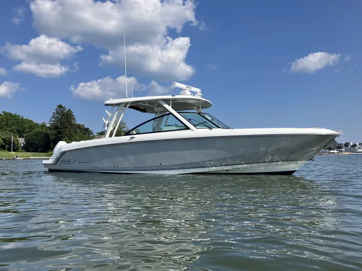  Yacht Photos Pics 2023 Boston Whaler 320 Vantage boat on calm water under a clear blue sky.