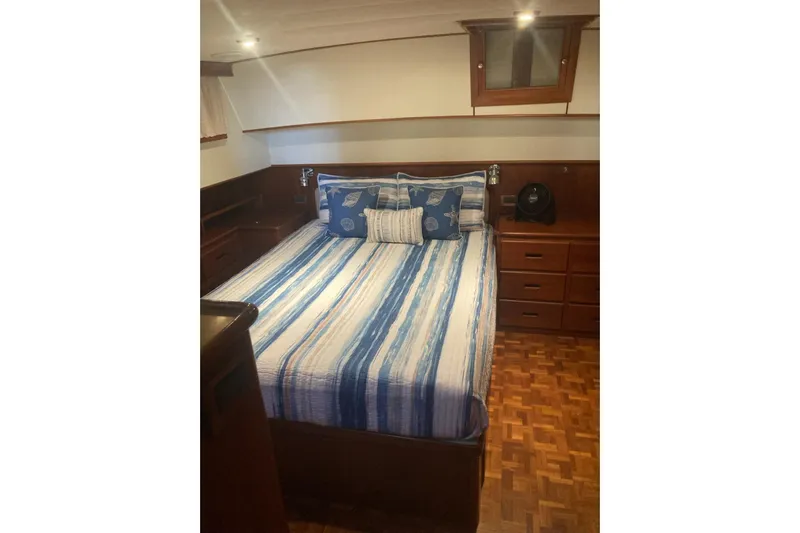 Gb421500 Yacht Photos Pics Cozy bedroom in 2002 Grand Banks 42 Classic yacht with striped bedding and wooden cabinetry.