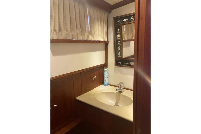 Gb421500 Yacht Photos Pics Bathroom interior of 2002 Grand Banks 42 Classic yacht with wooden cabinetry and decorative mirror.