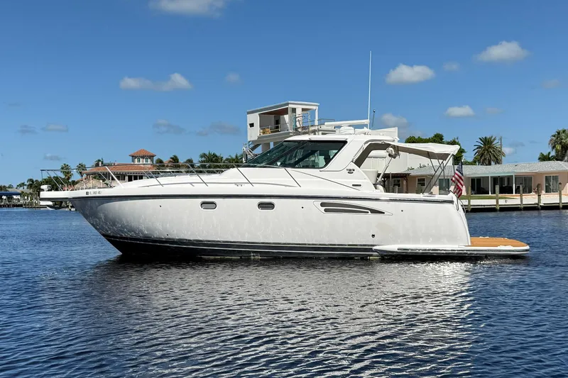 Blue Skys Yacht Photos Pics 2005 Tiara Yachts 3600 Sovran cruising on a sunny day, with waterfront homes in the background.