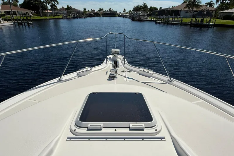 Blue Skys Yacht Photos Pics 2005 Tiara Yachts 3600 Sovran cruising on a serene waterway, surrounded by lush greenery.