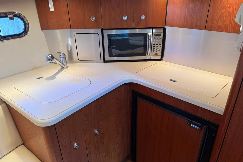 Blue Skys Yacht Photos Pics 2005 Tiara Yachts 3600 Sovran galley with microwave, sink, and wooden cabinetry.