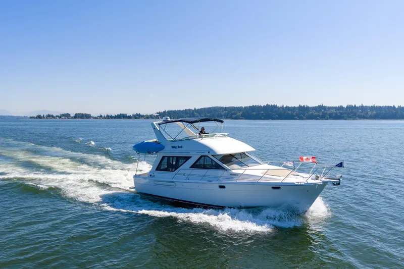  Yacht Photos Pics 1997 Bayliner 3988 cruising on a sunny day, with Canadian flag, scenic background.