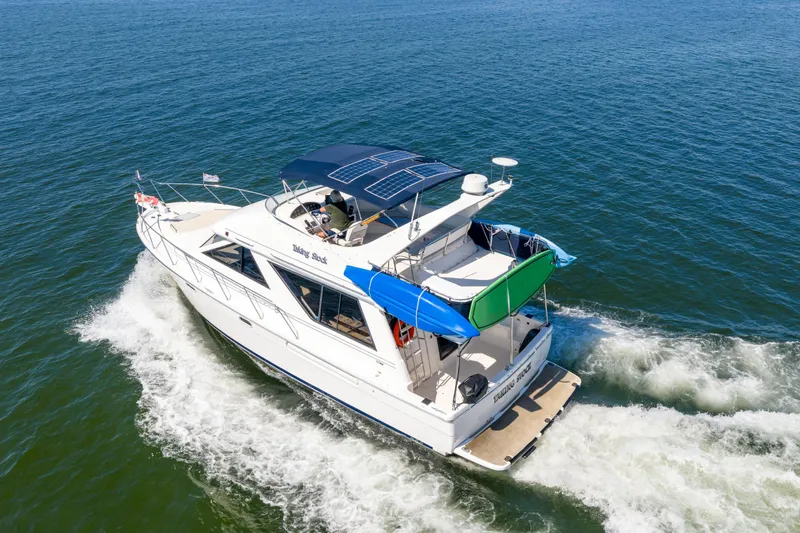  Yacht Photos Pics 1997 Bayliner 3988 yacht cruising on open water, featuring solar panels and colorful awnings.
