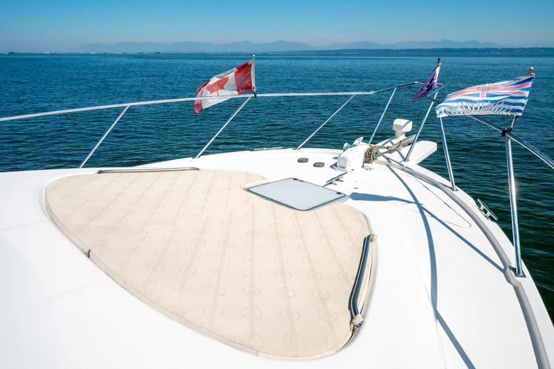  Yacht Photos Pics Bow of 1997 Bayliner 3988 yacht with flags, on calm blue water.