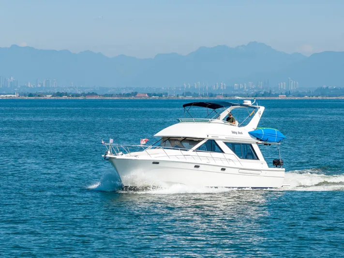  Yacht Photos Pics 1997 Bayliner 3988 yacht cruising on open water with city skyline in background.