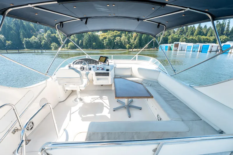  Yacht Photos Pics 1997 Bayliner 3988 yacht interior with helm, seating, and table on a scenic lake.