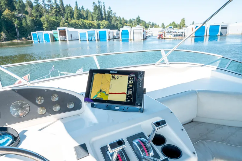  Yacht Photos Pics 1997 Bayliner 3988 yacht helm with navigation display, docked near blue and white boathouses.