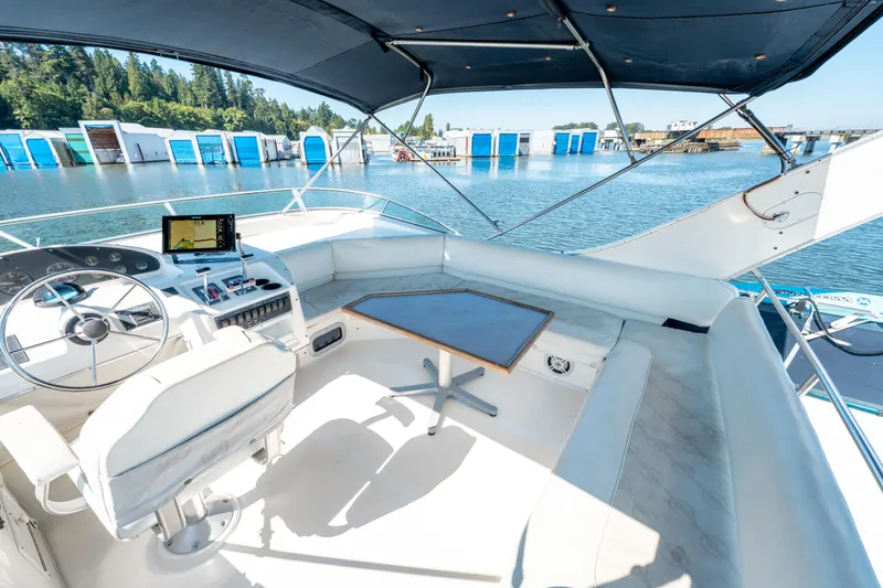  Yacht Photos Pics 1997 Bayliner 3988 yacht cockpit with steering wheel, seating, and navigation system, docked by blue boathouses.
