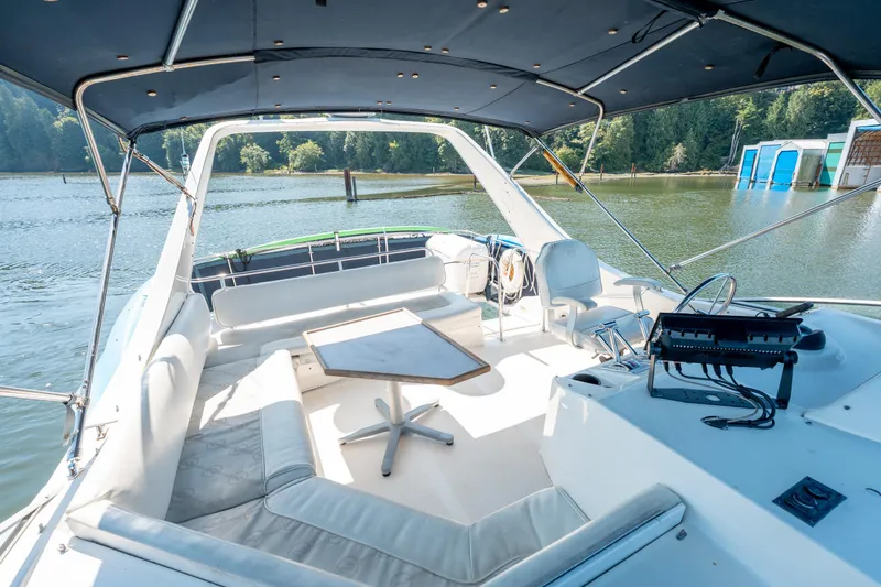  Yacht Photos Pics Spacious deck of 1997 Bayliner 3988 yacht with seating and table, docked by a serene lake.