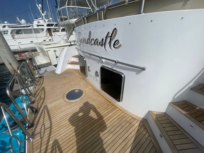 Sand Castle Yacht Photos Pics Luxury yacht deck with wooden flooring, featuring the name "Sandcastle," docked at a marina.