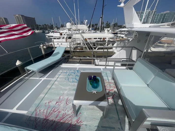Sand Castle Yacht Photos Pics Luxurious yacht deck with modern seating, table, and American flag, docked at marina.