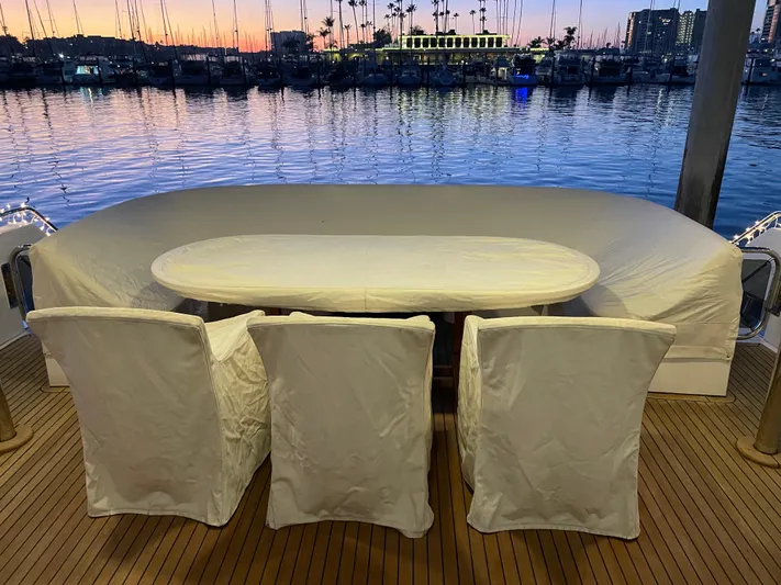 Sand Castle Yacht Photos Pics Outdoor dining setup on a 1996 Johnson 70 Euro yacht at sunset, overlooking a marina.