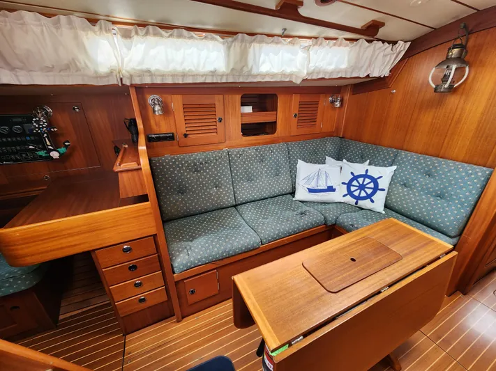 Vivace 1 Yacht Photos Pics Cozy interior of 2002 Hallberg-Rassy 36 MKII yacht with wooden furnishings and nautical-themed cushions.