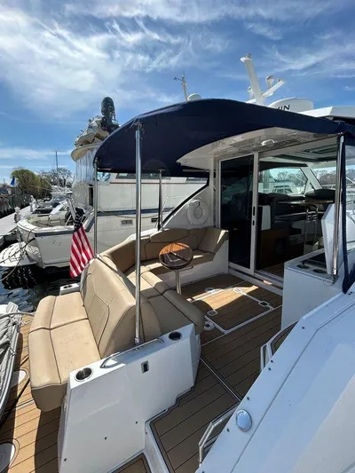  Yacht Photos Pics 2014 Cruisers Yachts 41 Cantius with outdoor seating, canopy, and American flag, docked under blue sky.