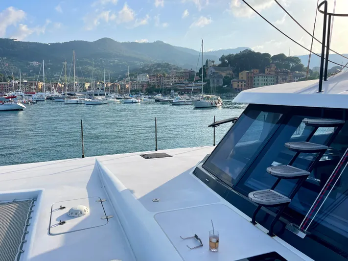  Yacht Photos Pics Sunreef 62 yacht in scenic harbor, 2018 model, with mountains and boats in the background.