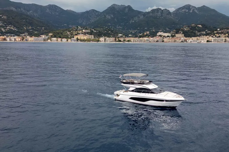  Yacht Photos Pics 2024 Princess F45 yacht cruising near coastal city with mountainous backdrop.