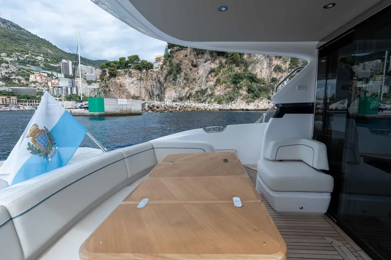  Yacht Photos Pics Luxurious 2024 Princess F45 yacht deck with scenic coastal view and flag.