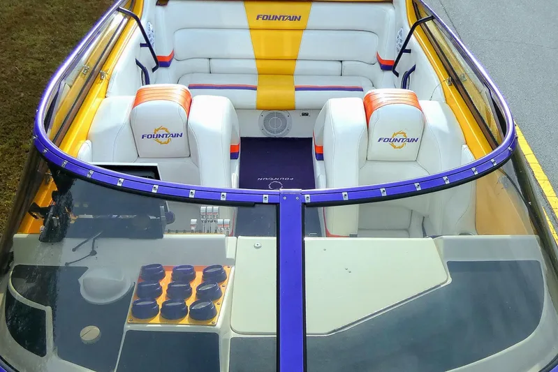  Yacht Photos Pics 2006 Fountain 47 Lightning boat interior with white and orange seating, purple trim, and dashboard controls.