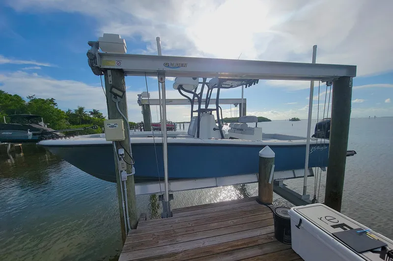  Yacht Photos Pics 2021 Yellowfin 26 Hybrid boat on lift at sunny waterfront dock.