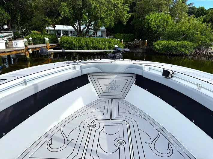  Yacht Photos Pics 2021 Yellowfin 26 Hybrid boat interior with custom flooring, docked near lush greenery.