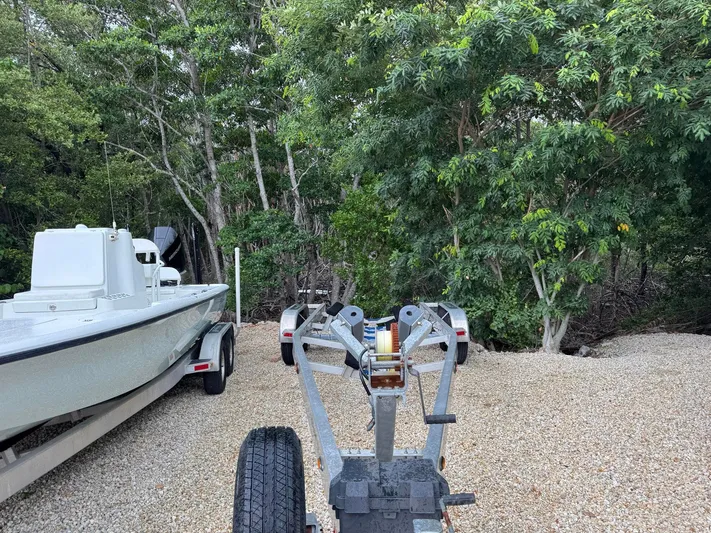  Yacht Photos Pics 2021 Yellowfin 26 Hybrid boat on trailer, surrounded by lush green trees.
