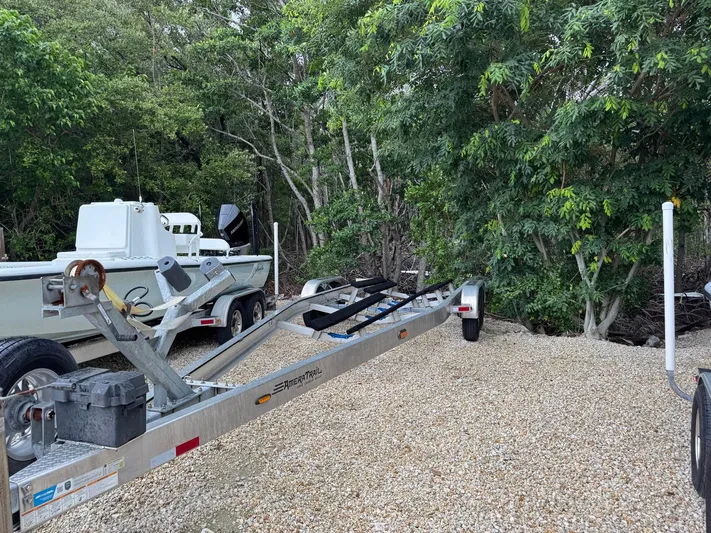  Yacht Photos Pics 2021 Yellowfin 26 Hybrid boat on trailer, surrounded by lush greenery.