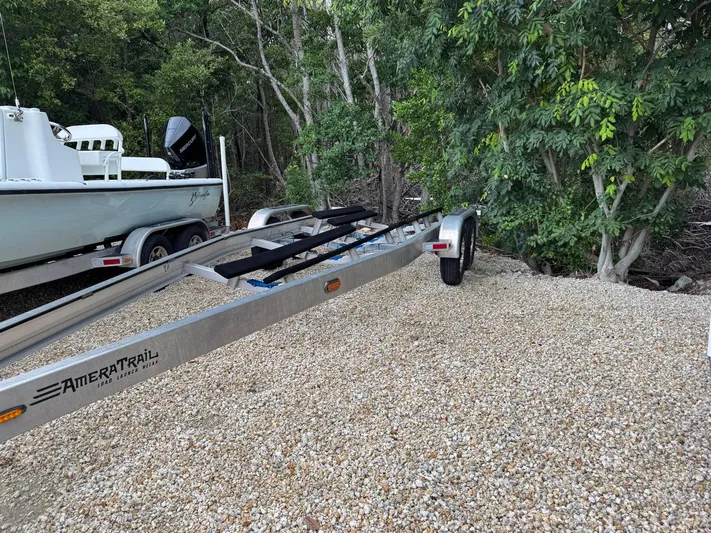  Yacht Photos Pics 2021 Yellowfin 26 Hybrid boat on AmeraTrail trailer, parked on gravel near trees.