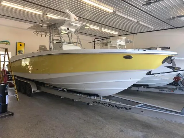  Yacht Photos Pics 2004 Boston Whaler 320 Outrage boat in a garage, yellow and white hull, on a trailer.