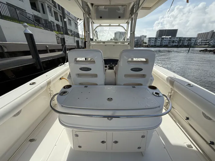  Yacht Photos Pics 2004 Boston Whaler 320 Outrage boat interior, featuring seating and storage, docked by waterfront buildings.